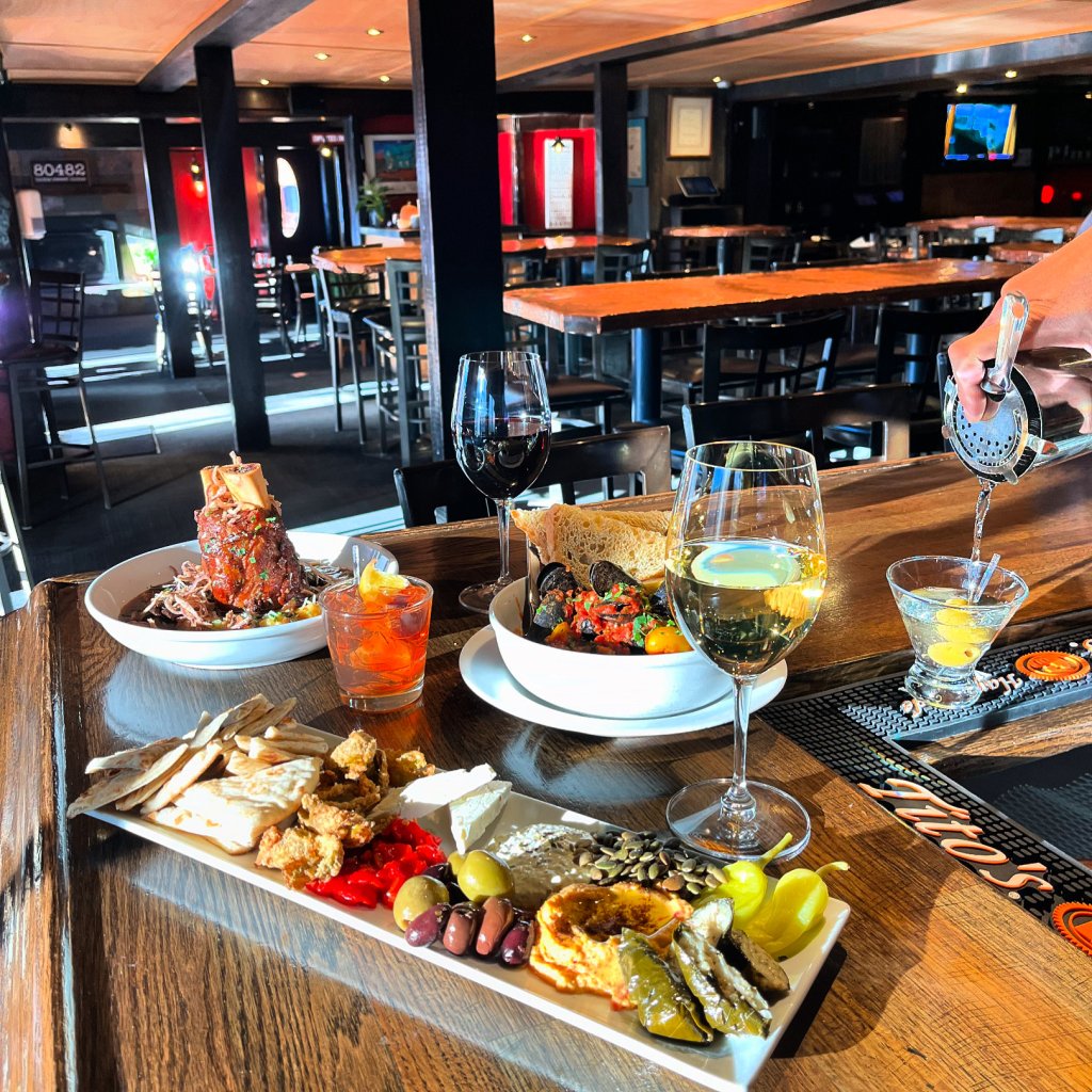 A restaurant table set with wine, cocktails, and a variety of Mediterranean-style dishes in Grand County Colorado.
