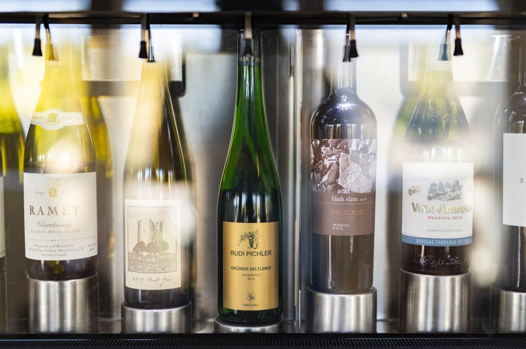 Close-up of wine bottles displayed at Adventures Decanted, including Ramey Chardonnay, Pinot Gris, Rudi Pichler Grüner Veltliner, Black Slate Escaladei, and Viña Ardanza Reserva.
