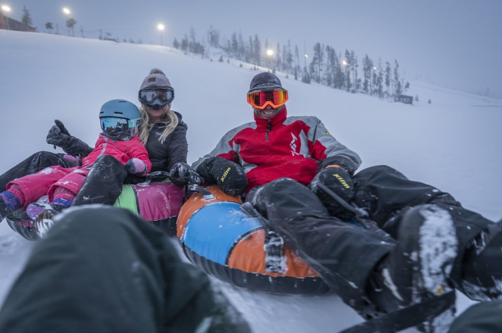 Group tubing down snowy slope at Fraser Tubing Hill.