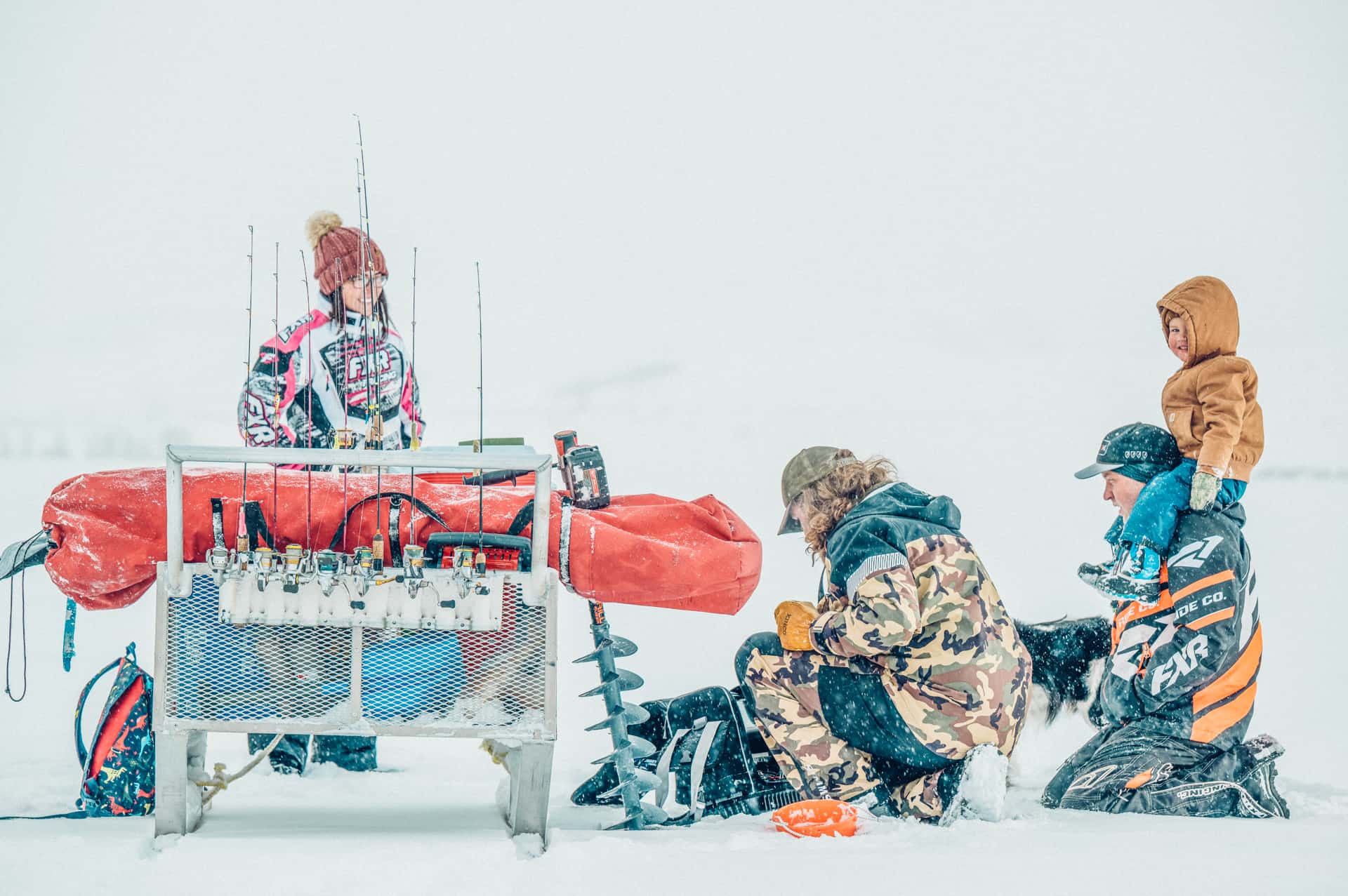 A group of people standing in the snow with a fishing rod.