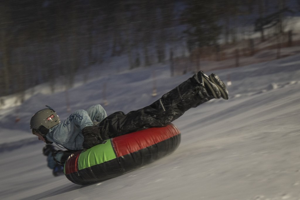 Person tubing down snowy slope at Coca-Cola Tubing Hill in Winter Park.