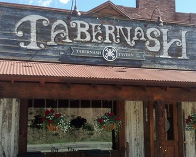 A rustic wooden building with a sign reading 'Tabernash' and hanging flower baskets in Grand County Colorado.