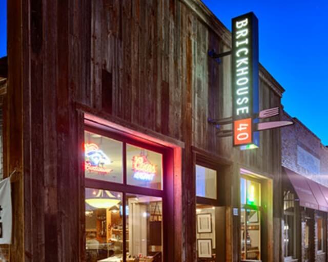 A rustic brick restaurant with a neon sign and illuminated vertical menu board in Grand County Colorado.