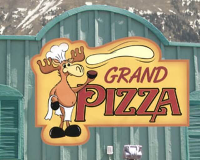 A cartoon moose wearing a chef's hat and apron serves pizza at Grand Pizza in Grand County Colorado.