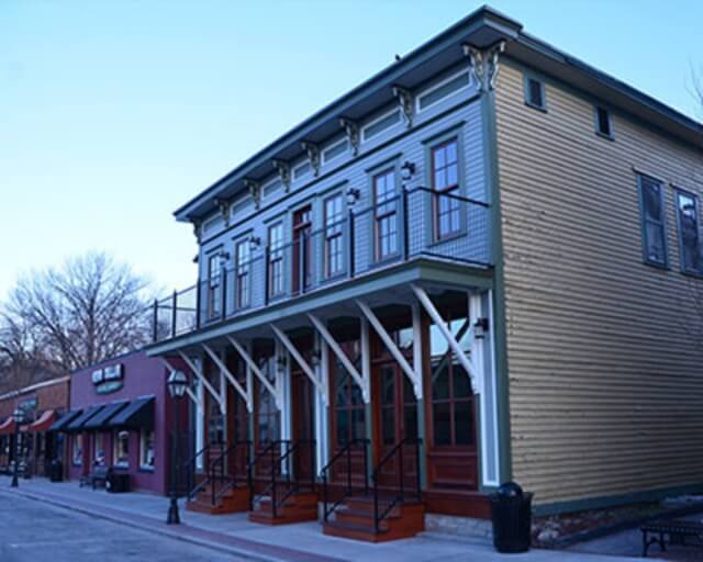 A two-story Victorian-style building with a wrap-around porch and colorful storefronts in Grand County Colorado.