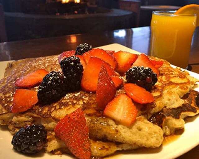 Stack of pancakes topped with strawberries, blackberries, and a glass of orange juice in Grand County Colorado.