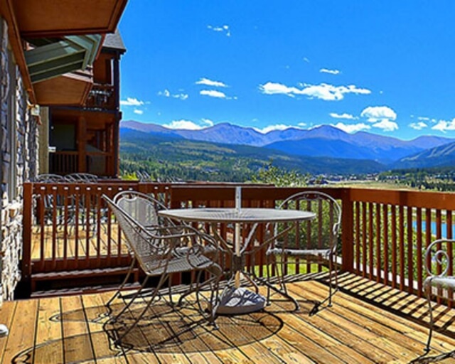 A wooden deck with a table and chairs overlooks a scenic mountain valley in Grand County Colorado.