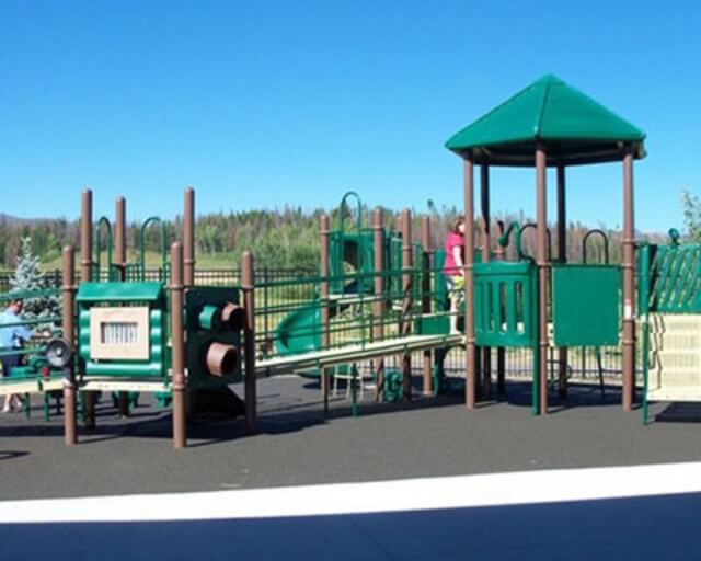 A colorful playground with a slide, climbing structures, and a gazebo-like shelter in Grand County Colorado.