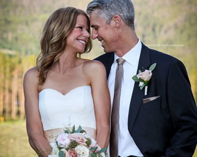 A smiling bride and groom share a tender moment outdoors, surrounded by nature in Grand County Colorado.
