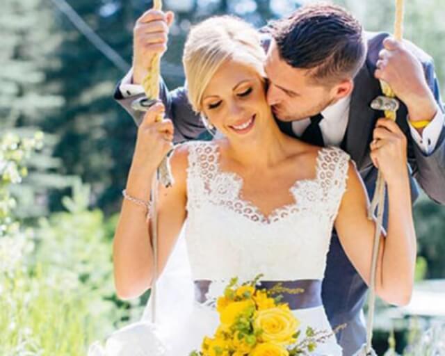 A bride and groom swing together in a garden, sharing a tender kiss in Grand County Colorado.