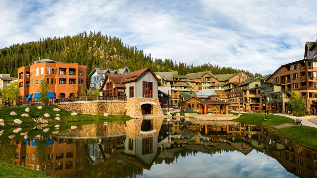 A serene mountain village with colorful buildings reflected in a calm pond in Grand County Colorado.
