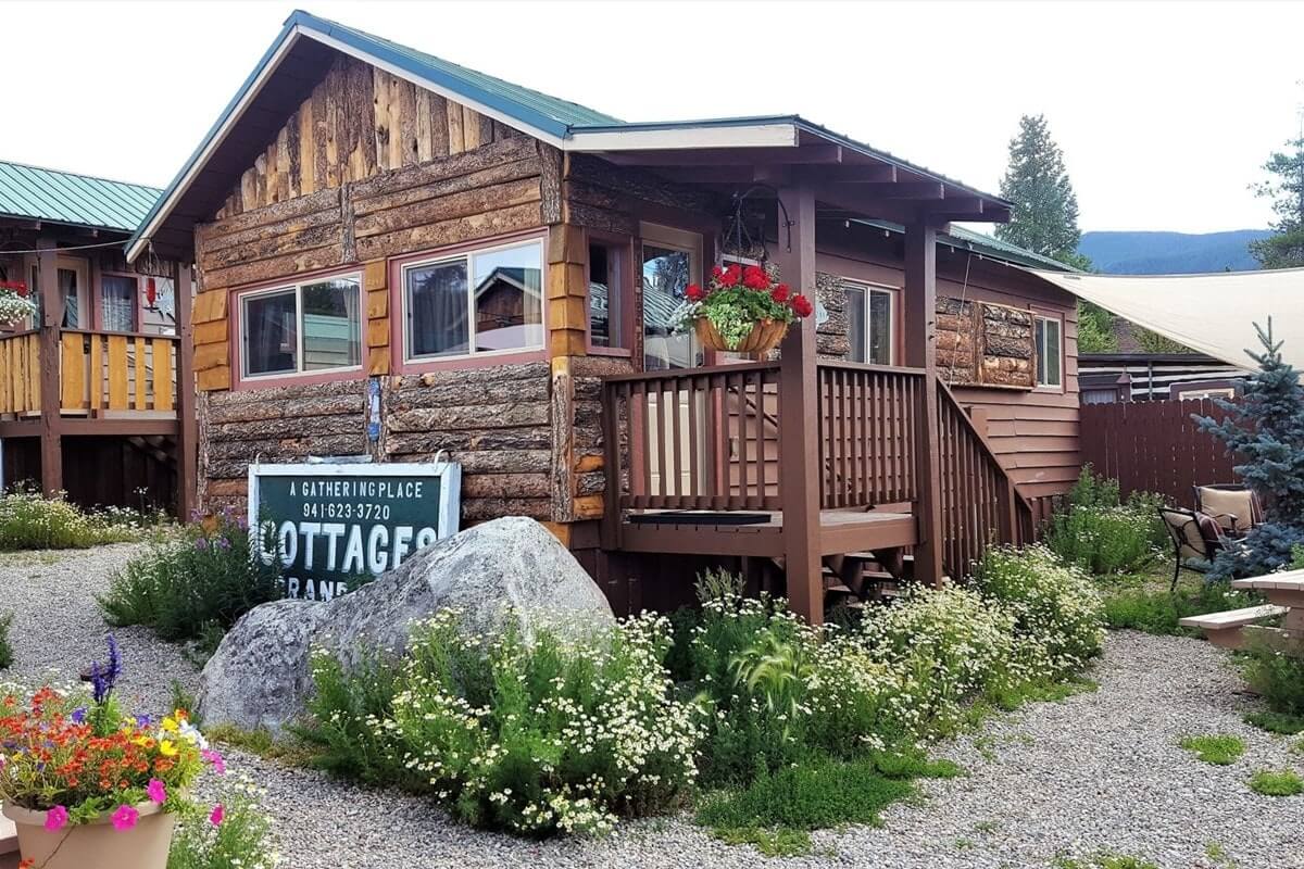 Rustic log cabin with flower garden and wooden deck in a natural setting in Grand County Colorado.