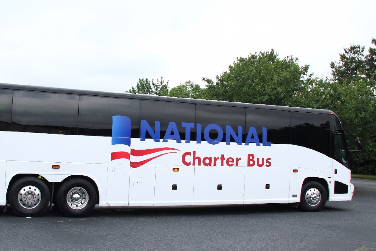 A large white charter bus with blue and red stripes and the words 'National Charter Bus' on the side in Grand County Colorado.