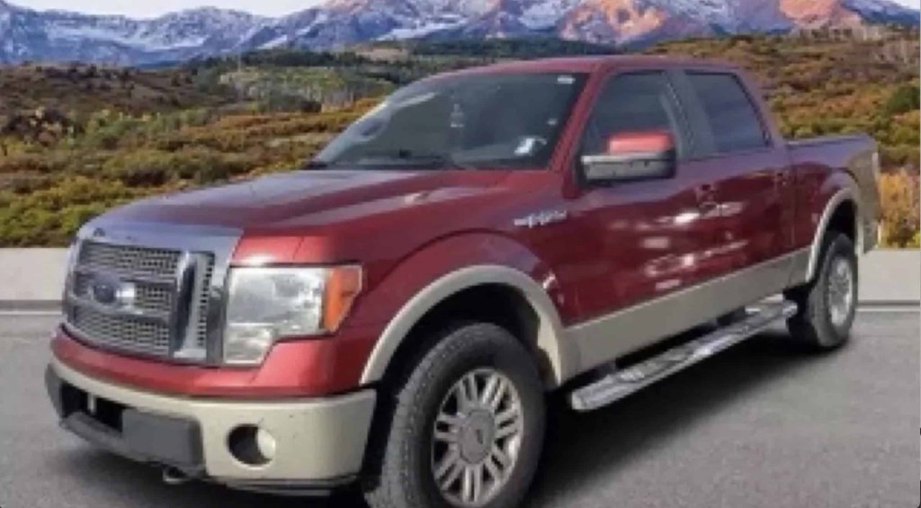 A maroon Ford F-150 pickup truck parked on a paved road with mountains in the background in Grand County Colorado.