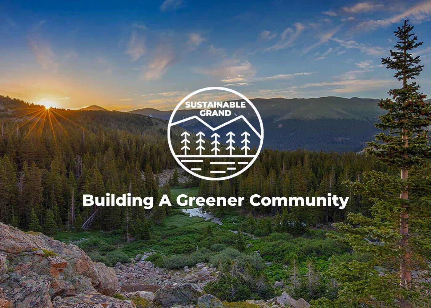 Sunrise over a lush, green forest with mountains in the distance in Grand County Colorado.