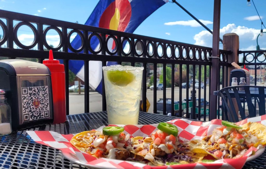 A plate of tacos with jalapeños and a glass of iced tea on a patio table in Grand County Colorado.