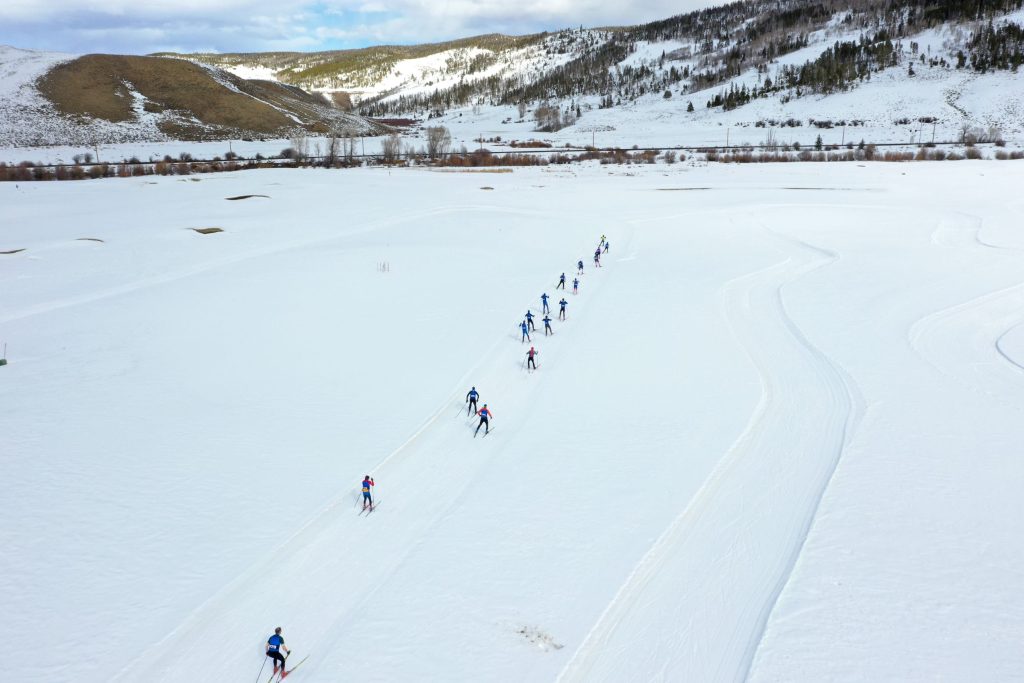 A group of cross-country skiers follows a winding trail through a snowy landscape in Grand County Colorado.