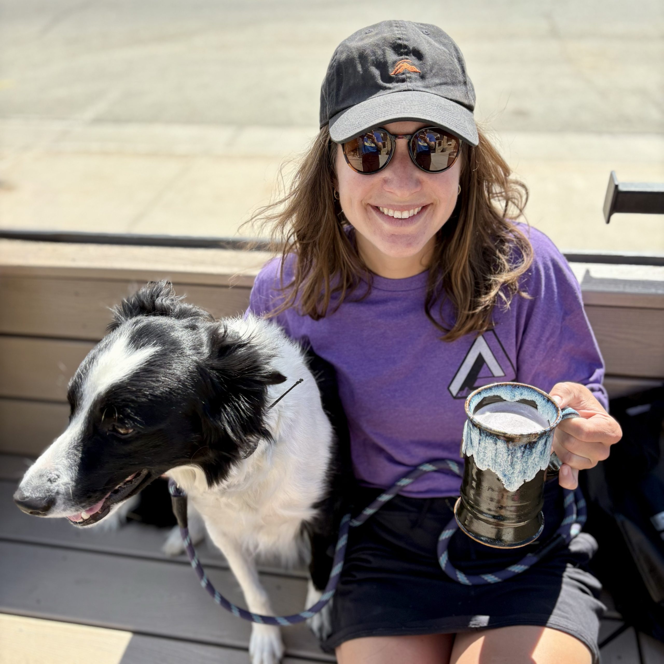 Smiling woman with a dog and ceramic mug on the patio at Hideaway Park Brewery.