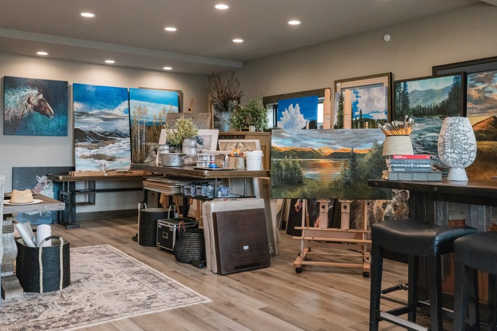 Art studio in Grand County filled with landscape and wildlife paintings, easels, and art supplies.
