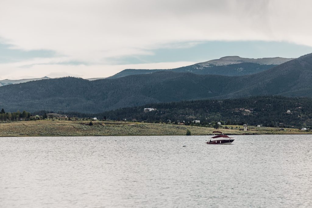 Boat floating on Granby Lake with forested mountains in the background.
