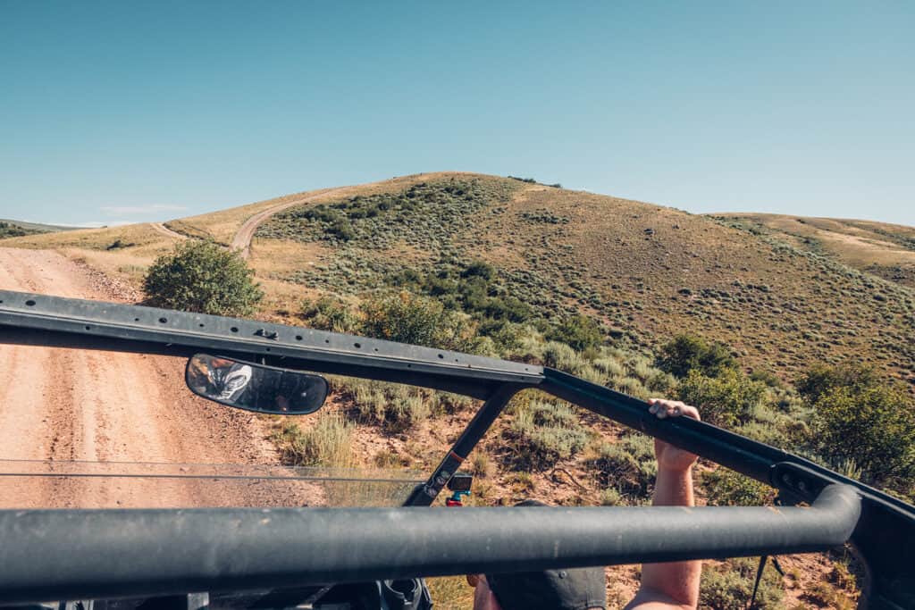 A man is driving a jeep down a dirt road.