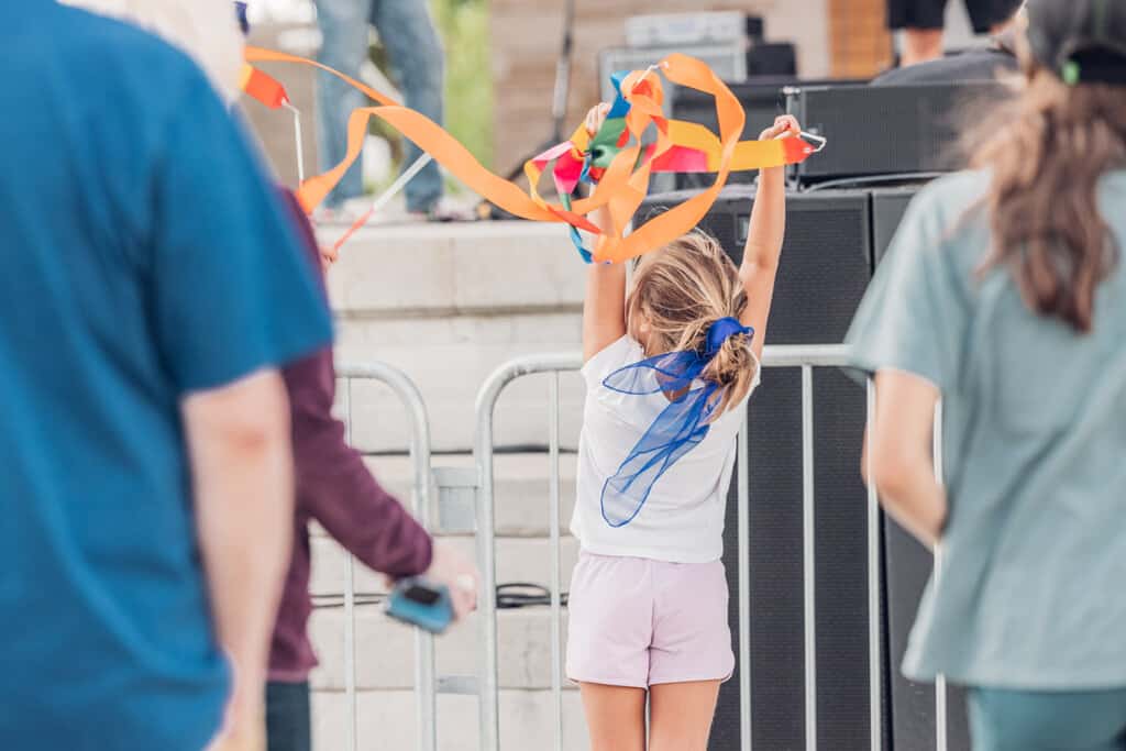 A girl is holding a kite in the air.