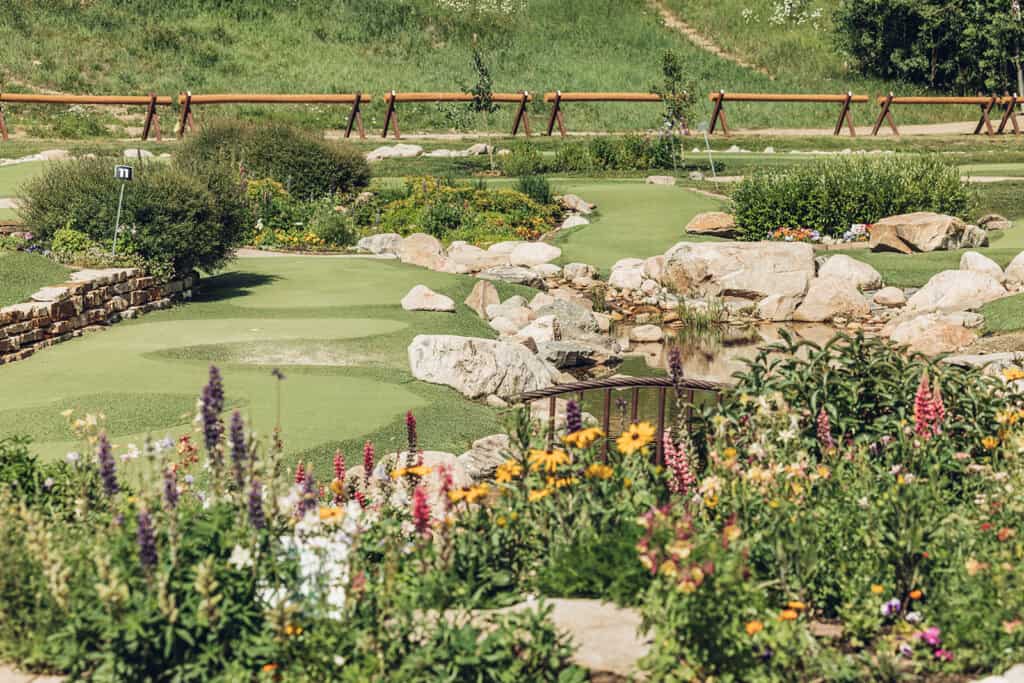 A mini golf course with flowers and rocks.