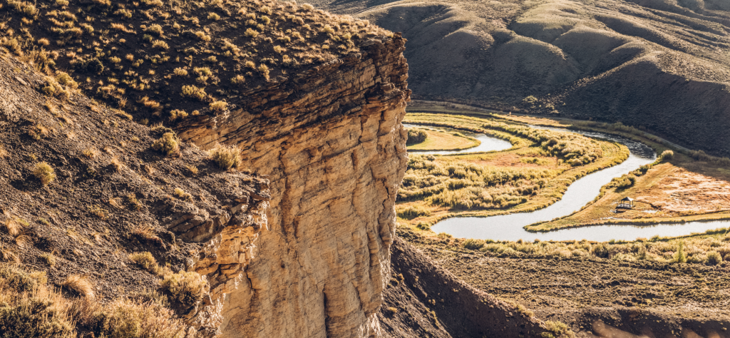 Winding river through Gore Canyon with steep rocky cliffs and rolling hills.